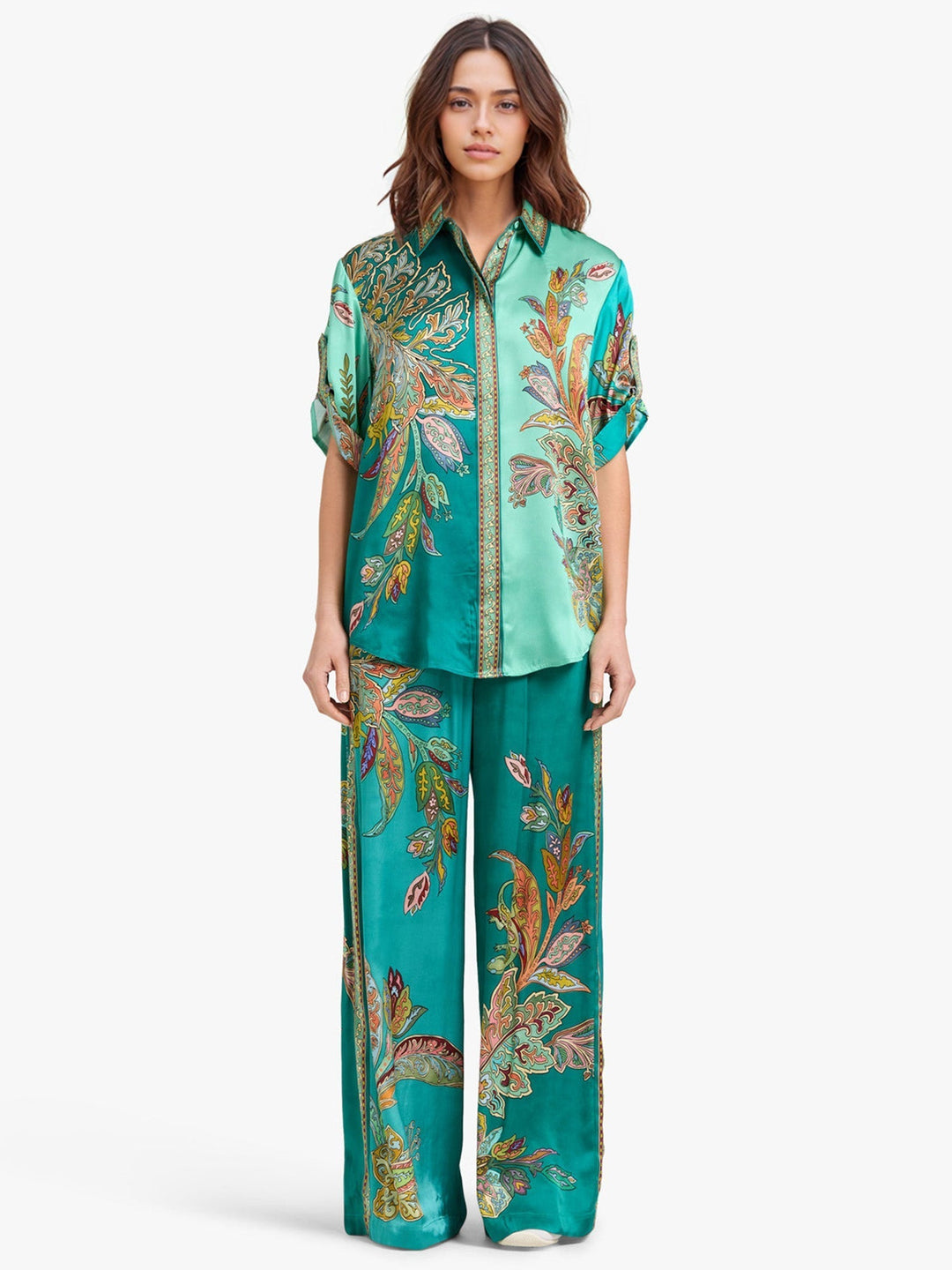 Model in full-length green two-piece set with paisley patterns, standing against a white studio background.