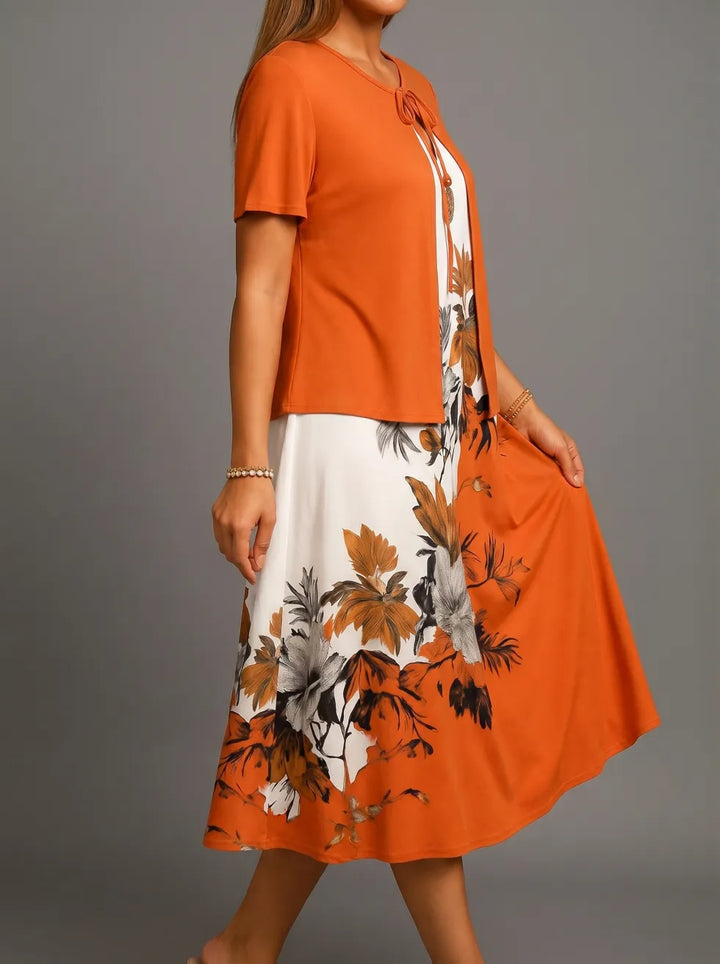 Side view of orange midi dress with floral design, short sleeves, and tie neck, in a studio setting.