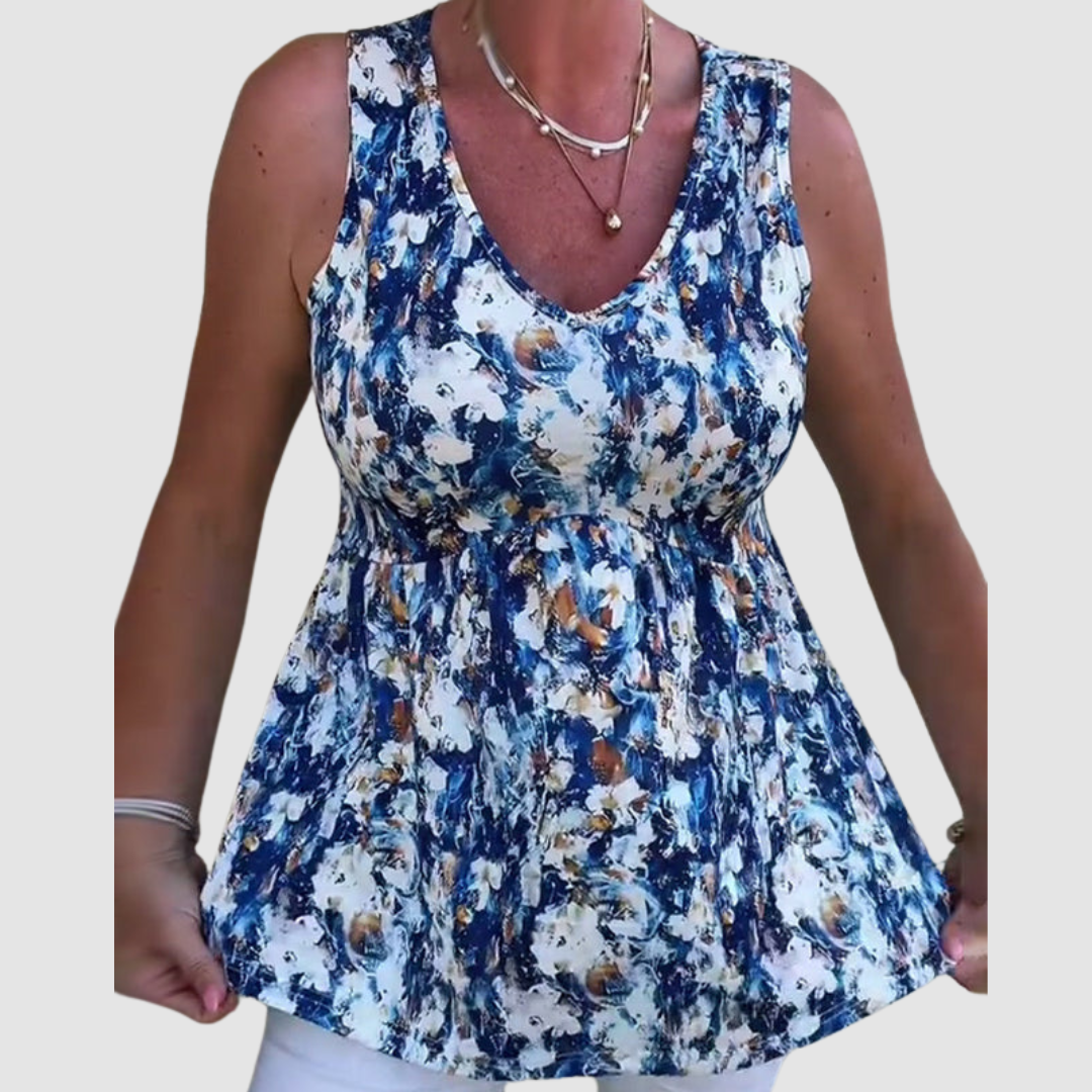 Woman in a blue and white abstract pattern sleeveless top, holding the hem in a studio setting.