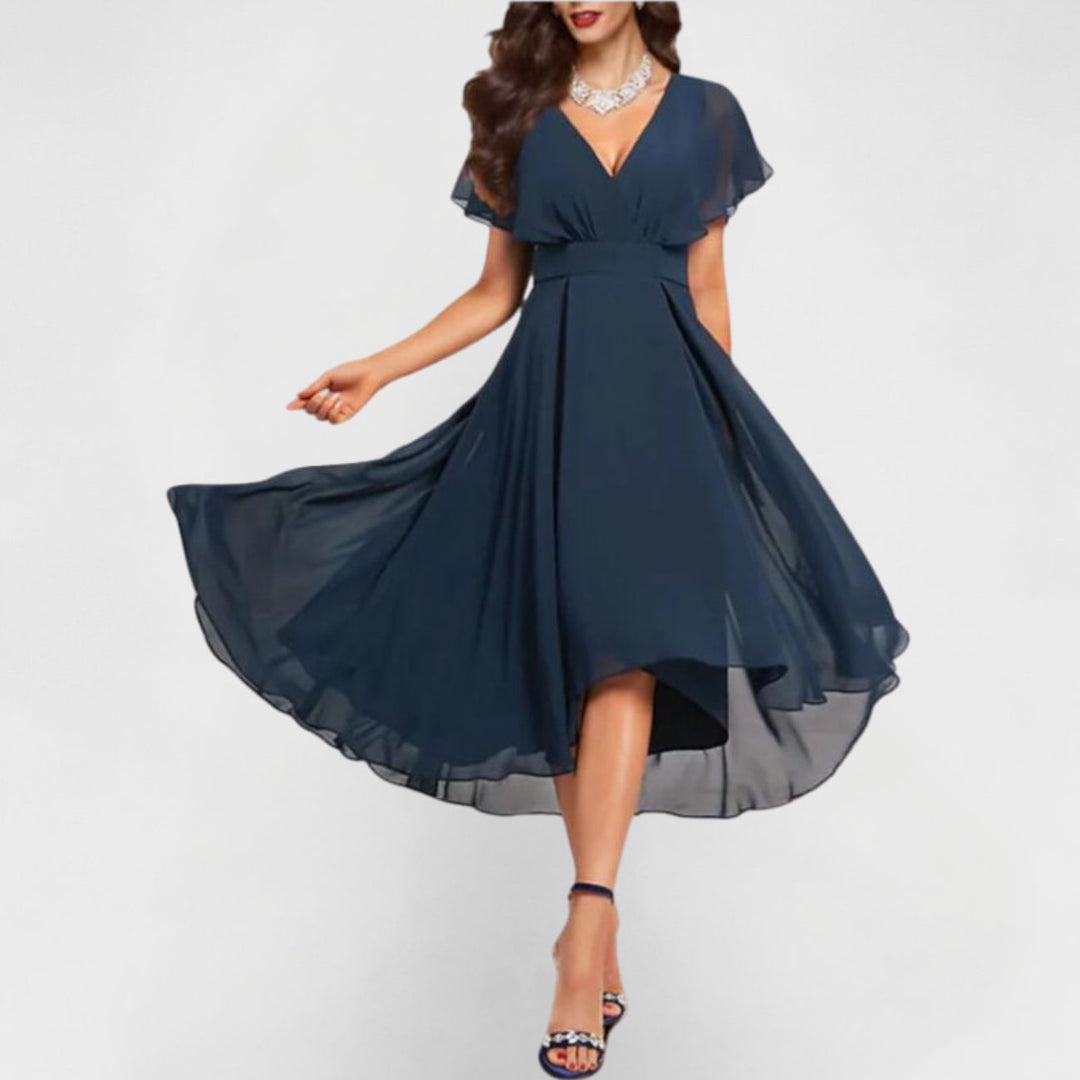 Woman in elegant navy flowing V-neck maxi dress with flared hem and short sleeves, twirling in a studio setting.