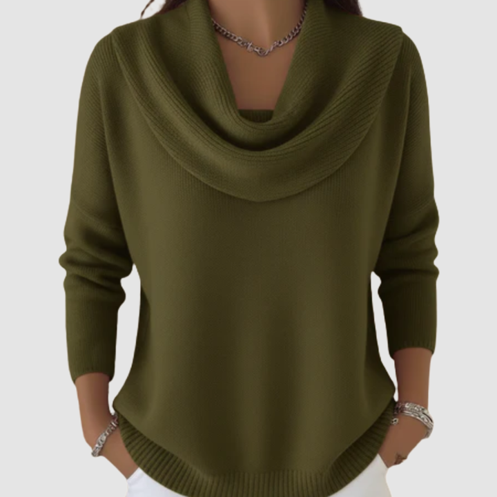 Olive green cowl neck sweater with long sleeves worn over white pants, displayed in a studio setting.