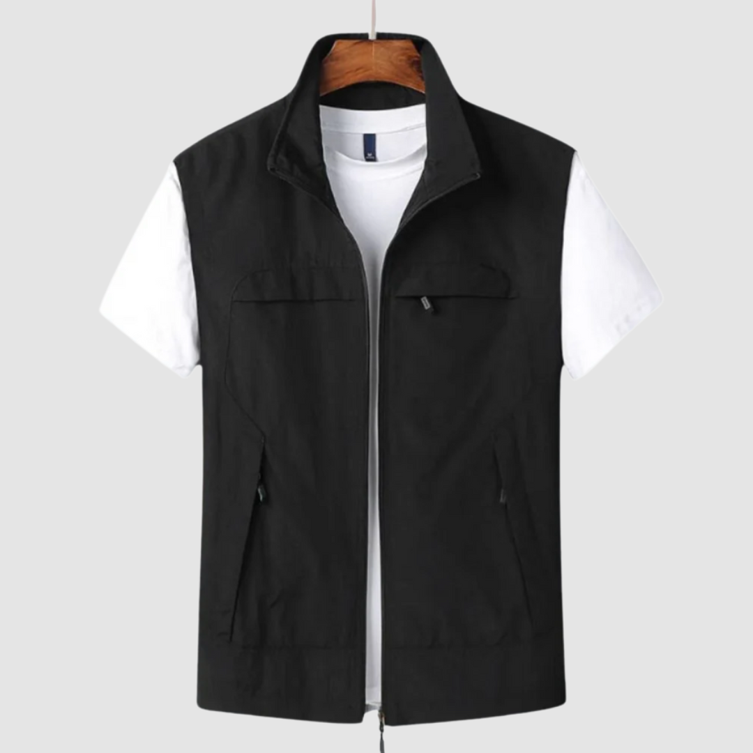 Black summer vest with zip closure and pockets, layered over a white t-shirt, on a hanger against a gray backdrop.
