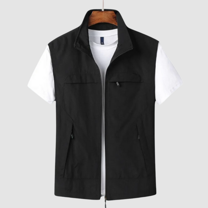 Black summer vest with zip closure and pockets, layered over a white t-shirt, on a hanger against a gray backdrop.
