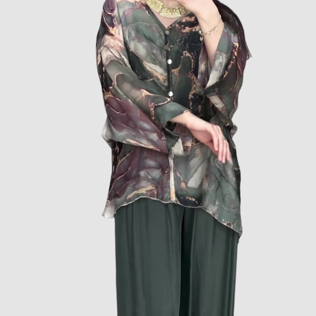 Model wearing an elegant printed two-piece set, showcasing button-up top with long sleeves and flowing pants in a bright setting.