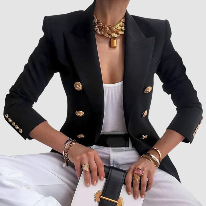 Elegant black blazer with gold buttons, worn over a white top and paired with chic gold accessories and holding a stylish handbag in a studio setting.