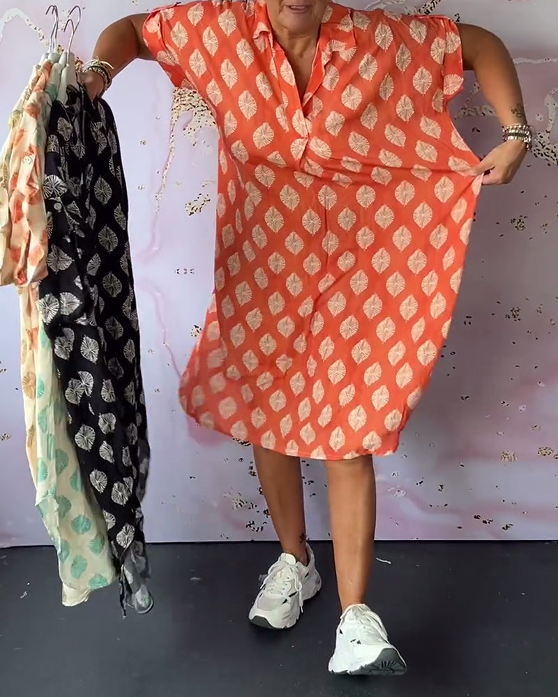 Model in orange dress holding patterned versions on hangers, paired with sneakers, in a studio with artistic decor.