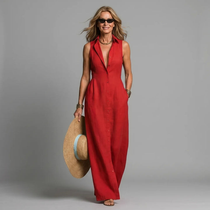 Woman in red maxi shirt dress, holding a straw hat, in a studio setting.