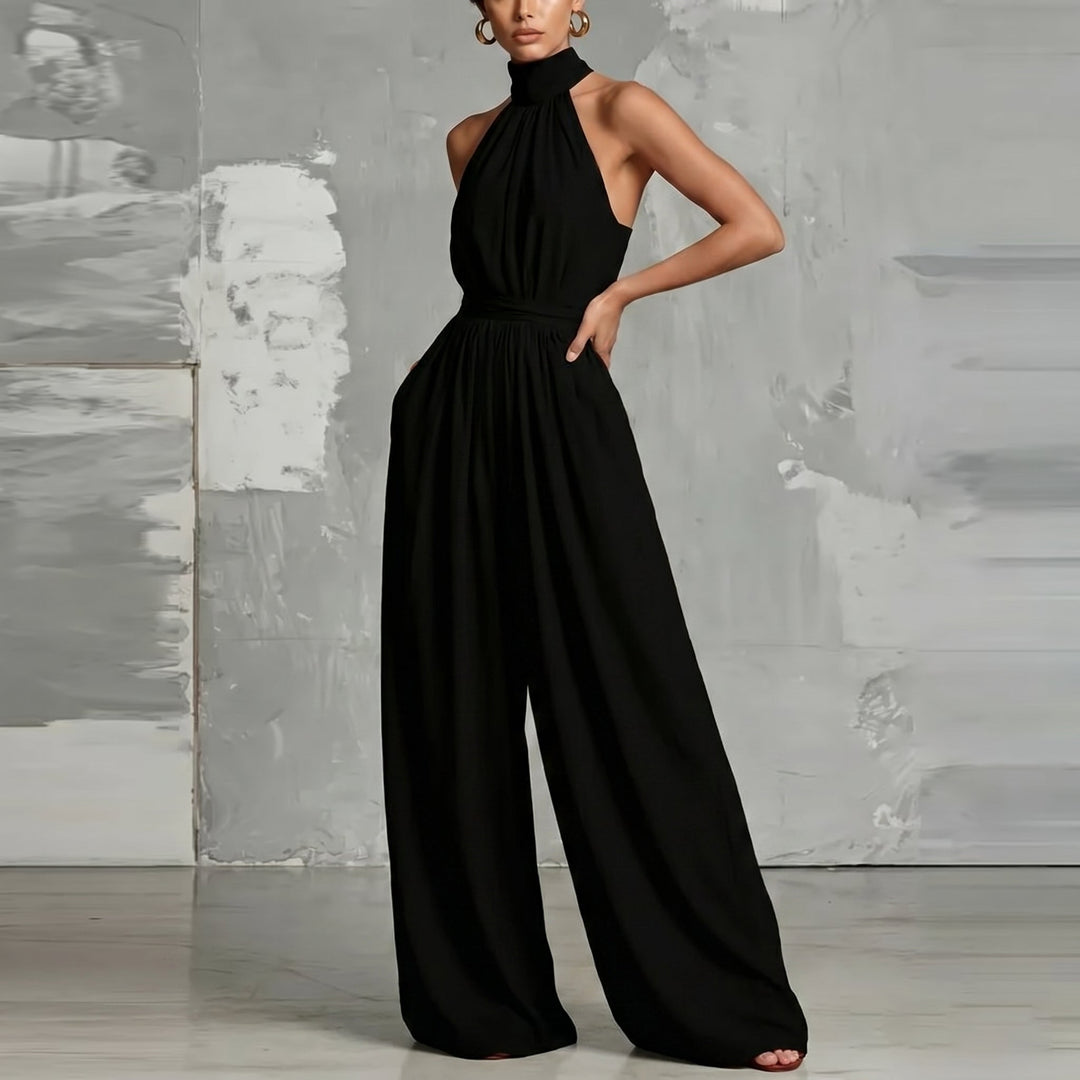 Stylish black halter-neck jumpsuit with flowing wide legs in a contemporary studio setting.