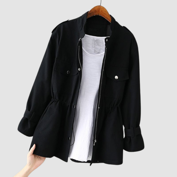 Black jacket featuring a zip front, drawstring waist, and front flap pockets, on a wooden hanger against a white backdrop.