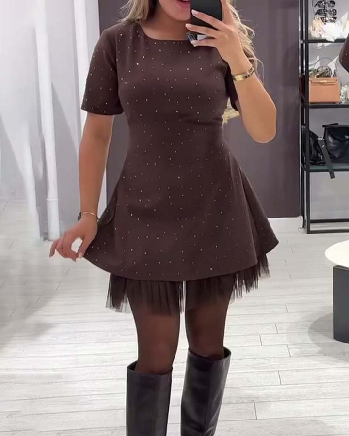 Brown dress with studded details, short sleeves, and tulle hem. Worn with thigh-high boots. Mirror selfie in modern store.