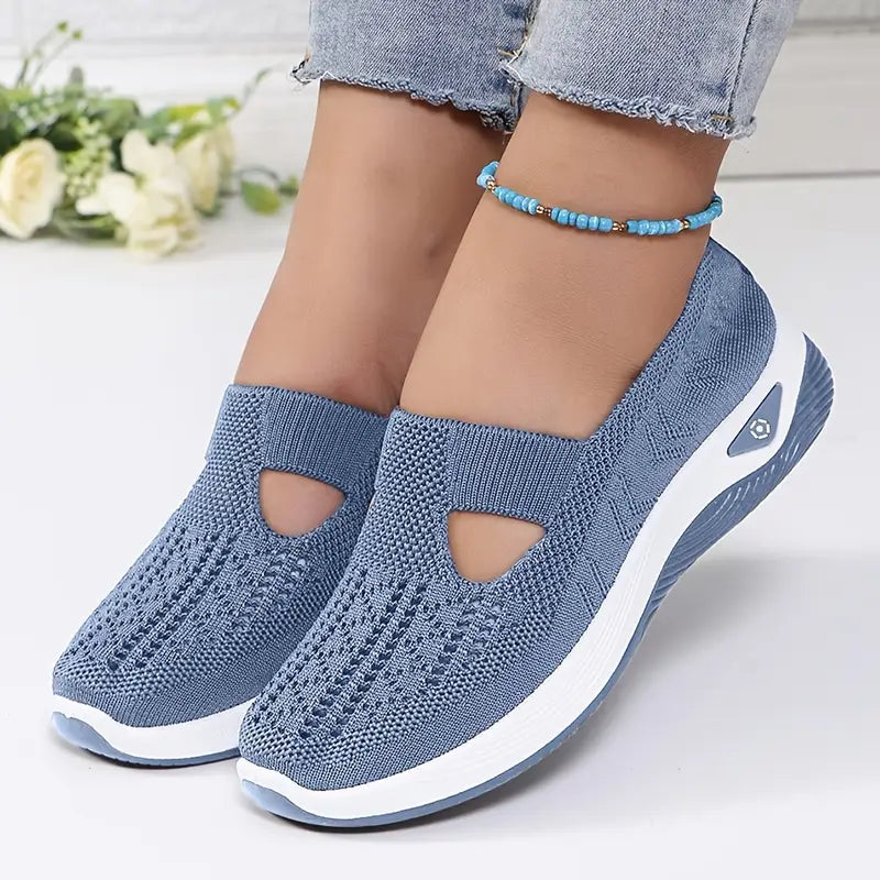 Blue non-slip orthopedic shoes worn with blue anklet, faded jeans on white background.