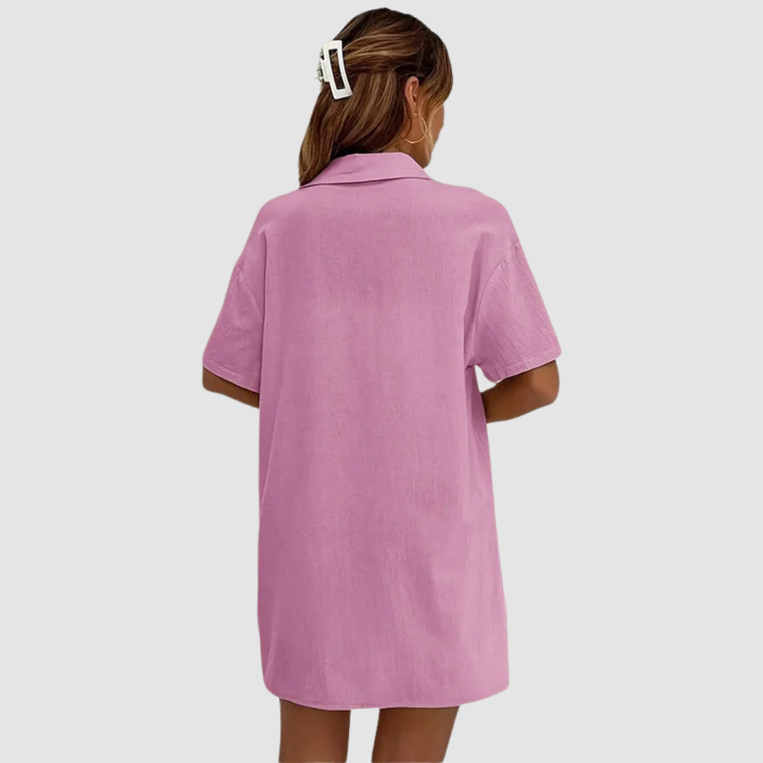 Back view of woman in pink button-up dress, hair clipped, against a studio background.