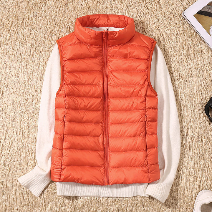 Orange puffer vest over a white sweater on a beige textured carpet, with accessories nearby.