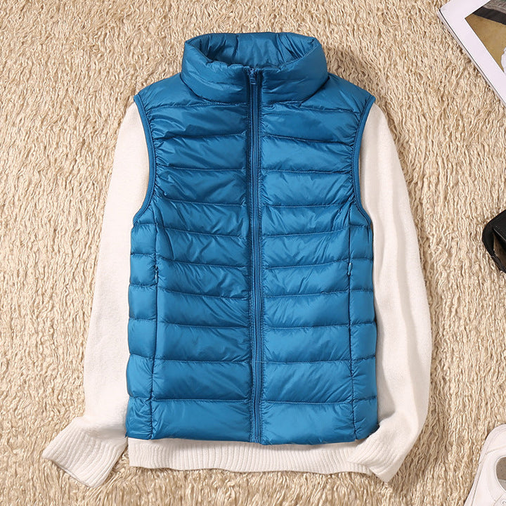 Blue puffer vest on a white sweater, displayed on a beige textured surface with nearby items.