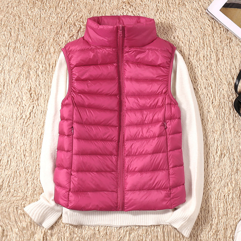 Hot pink puffer vest on a white sweater, on a beige textured carpet with accessories.