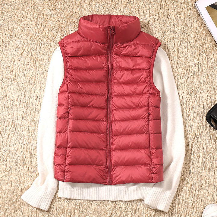 Red puffer vest displayed over a white sweater on a beige textured rug.