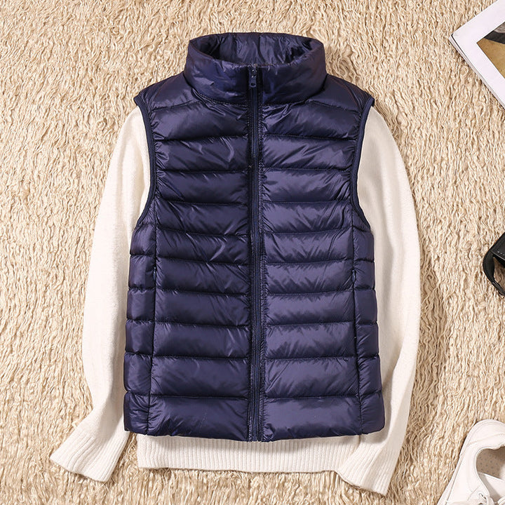 Dark blue puffer vest on a beige textured rug over a white sweater, nearby accessories.