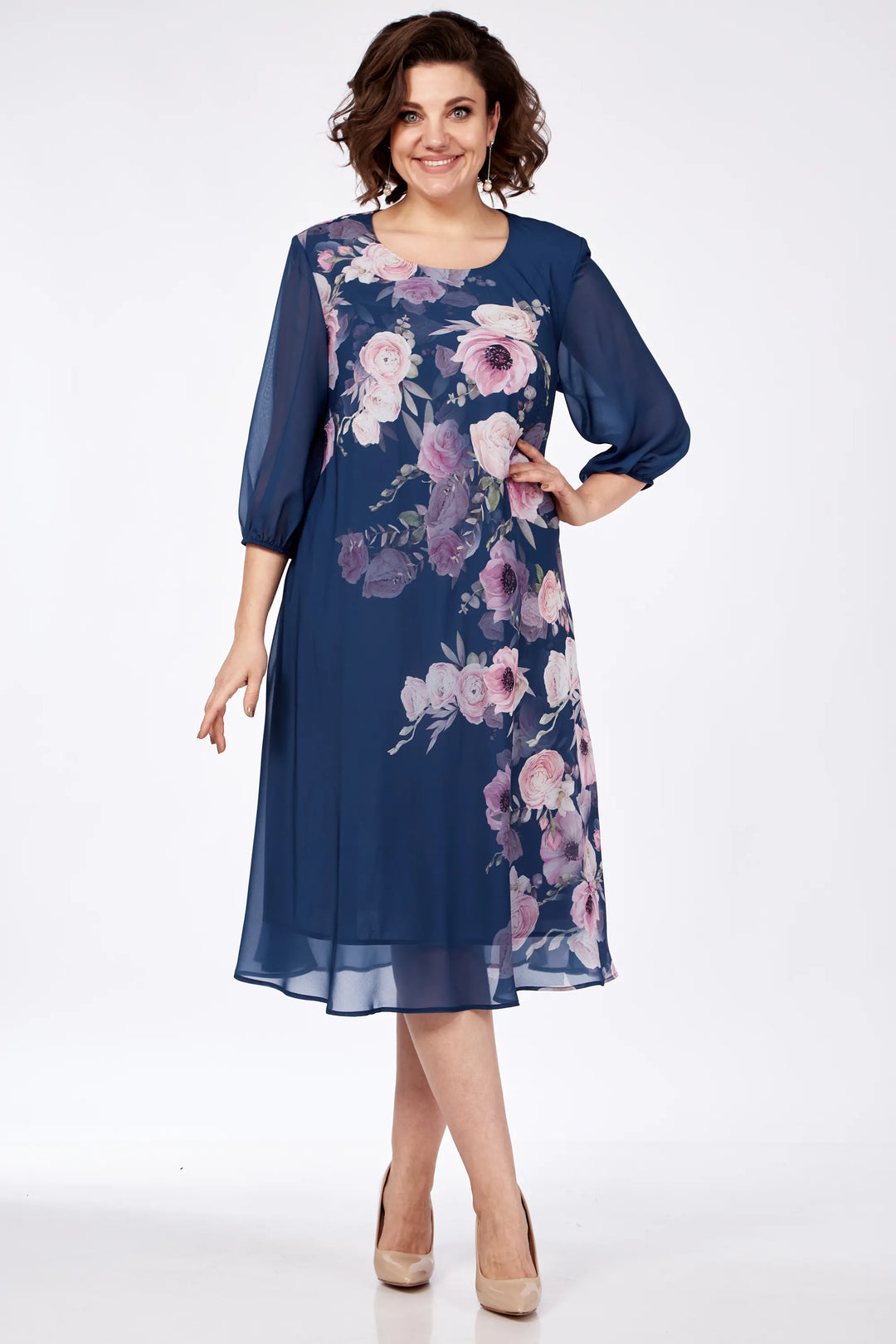 Model in a navy floral dress with pink accents, standing confidently in a studio setting.