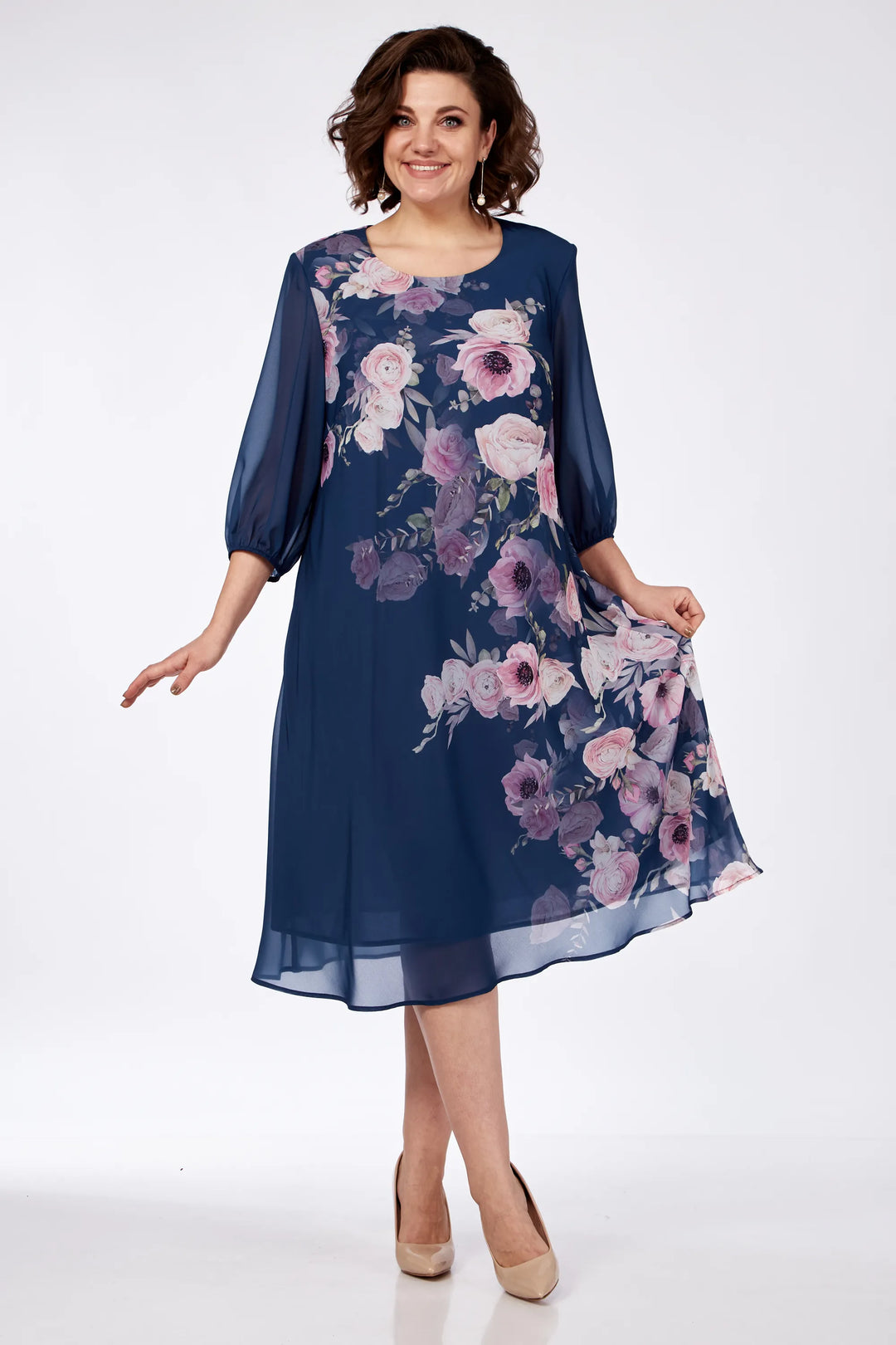 Model twirling in a navy floral dress, showcasing its flowing design in a white studio.