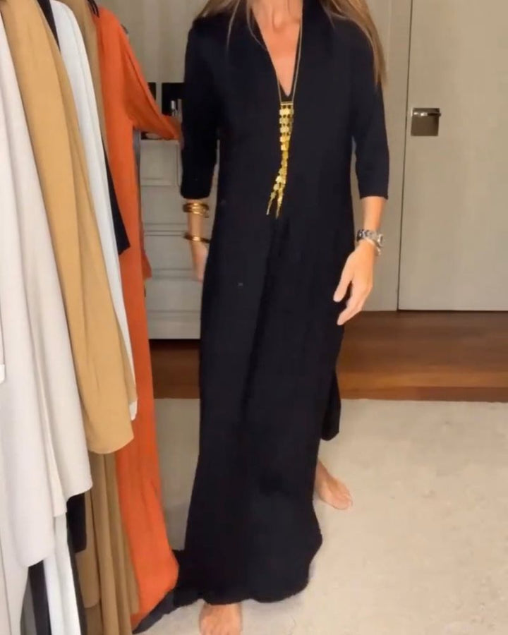 Person in a black casual maxi dress with three-quarter sleeves, next to a wardrobe with various clothes.