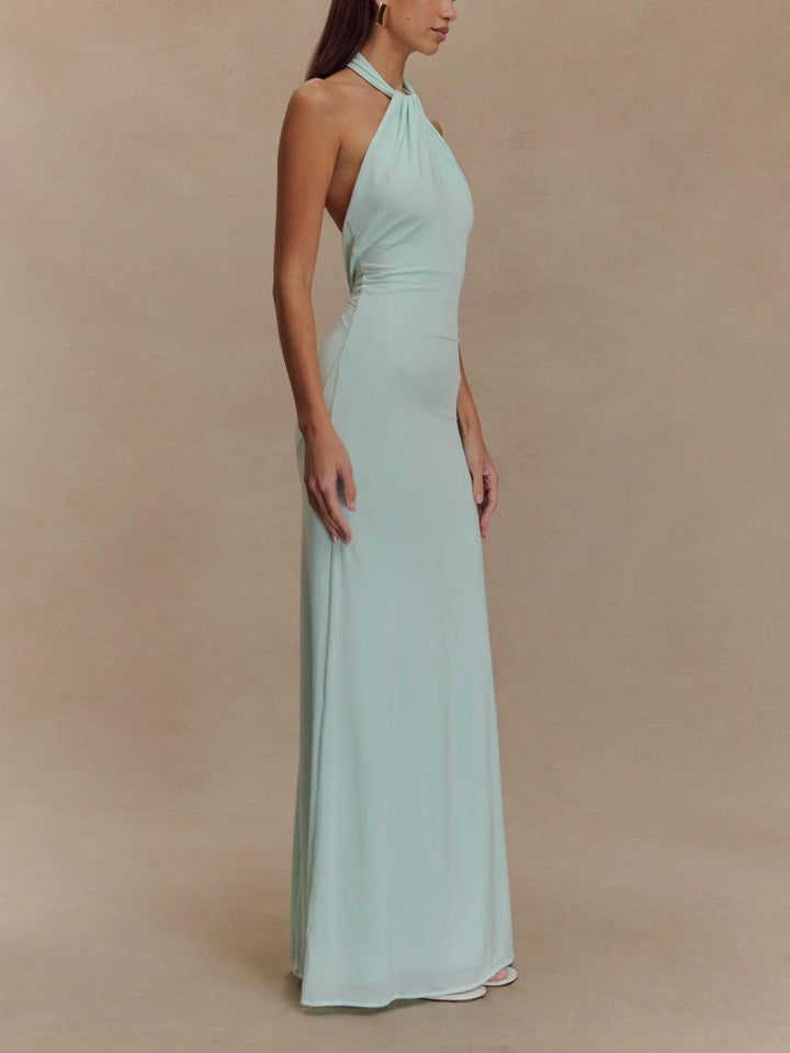 Side view of a light mint green slinky halter maxi dress worn by a model in a studio setting.