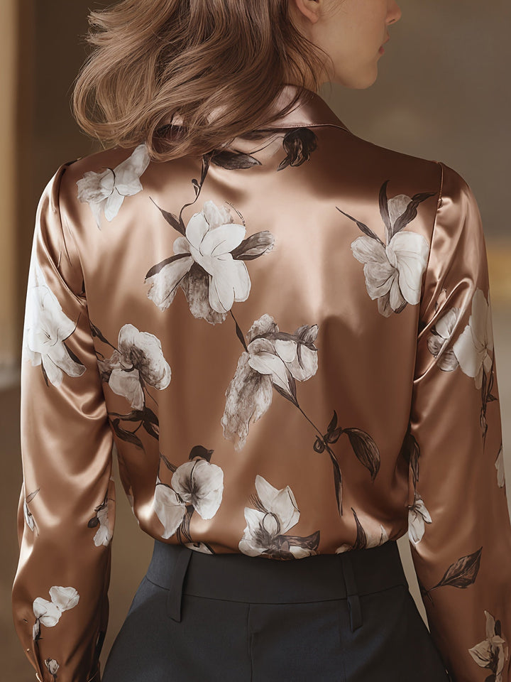 Backside of brown satin blouse with floral design, model indoors, facing soft lighting.