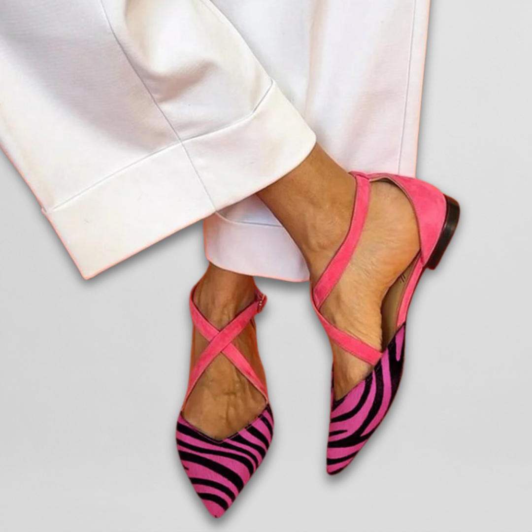 Pink ballet flats with pink zebra pattern, paired with white pants on a light gray background.