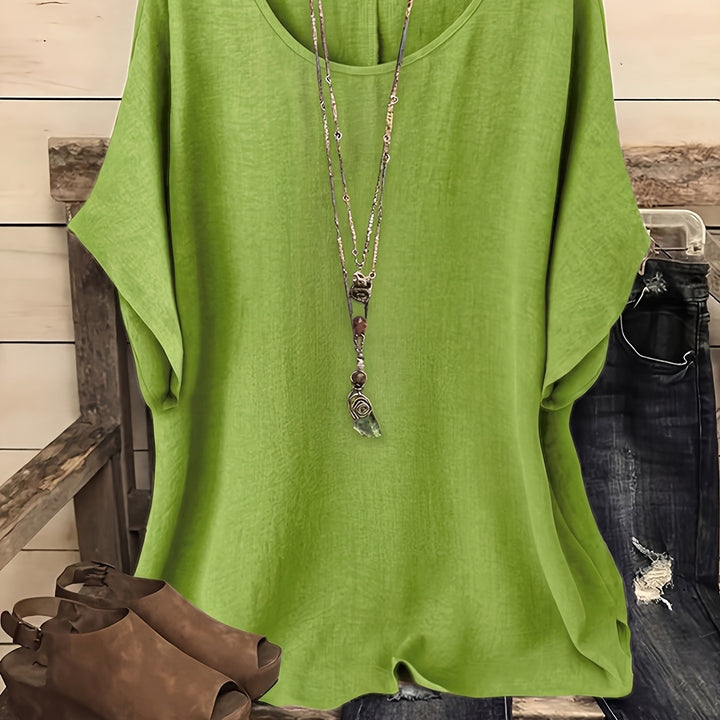 Bright green loose summer top on hanger with necklace, sandals, and jeans on rustic bench.