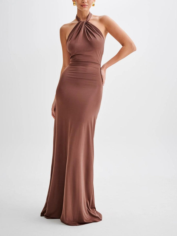 Model wearing a brown slinky halter maxi dress in a white studio setting.