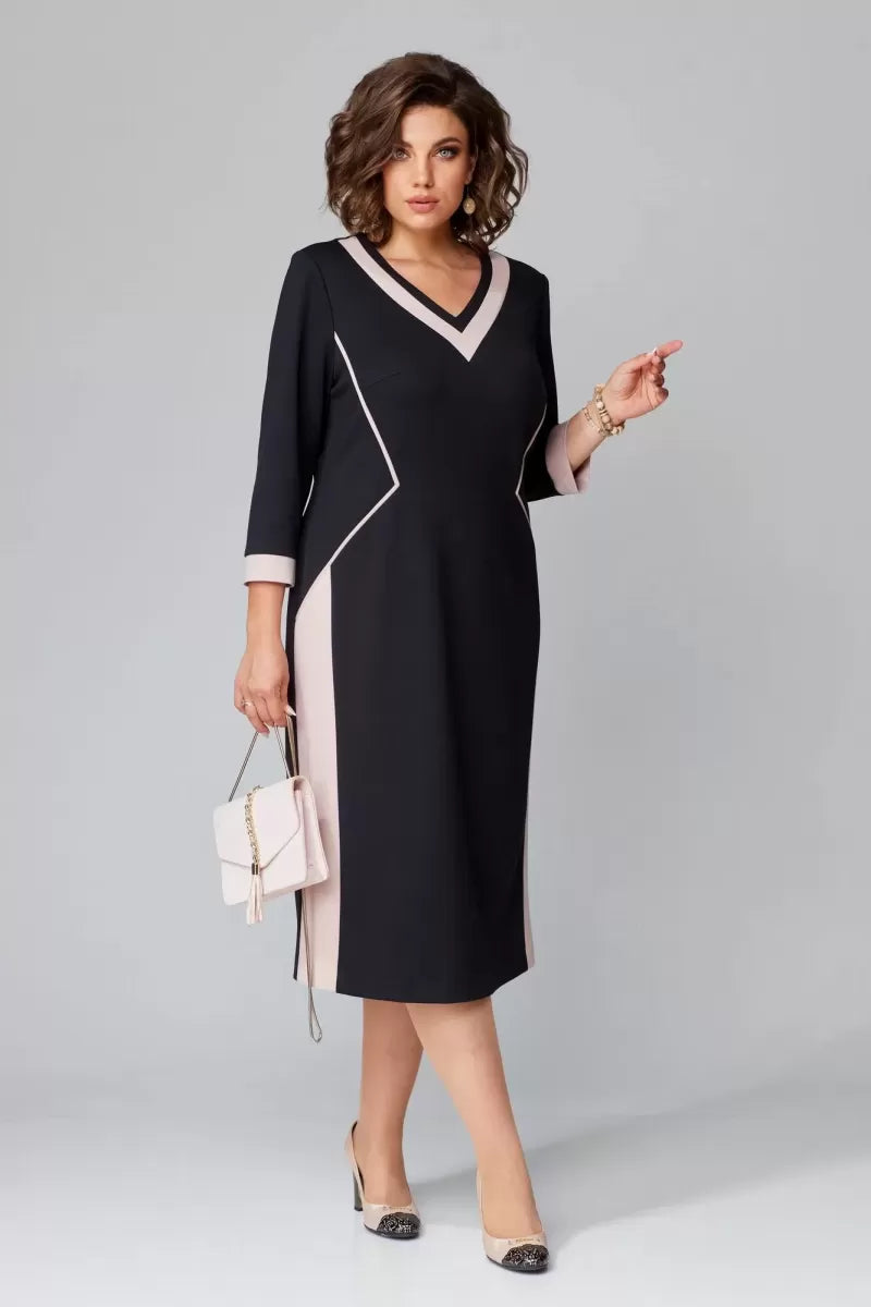 Model in black and pink V-neck dress with three-quarter sleeves, holding a beige handbag in a studio setting.