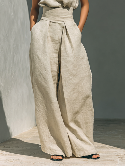 Close-up of high-waisted beige wide-leg pants in a minimalist outdoor setting.