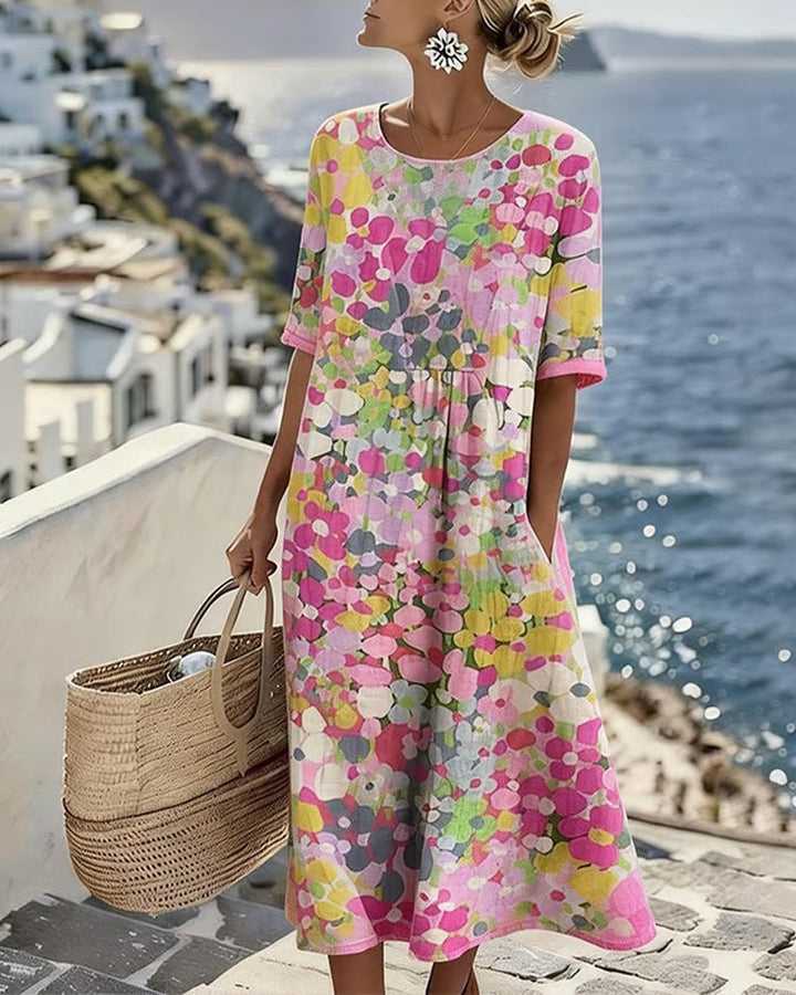 Woman in colorful floral midi dress on sunny seaside terrace with wicker bag, ocean view background.