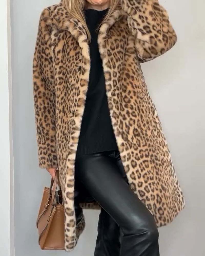Woman wearing a leopard print coat in warm brown tones, paired with black outfit and brown handbag in a simple indoor setting.