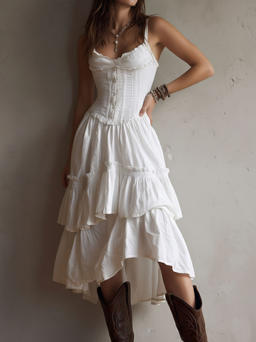 Model in white tiered midi dress, fitted bodice, brown boots. Neutral textured background.