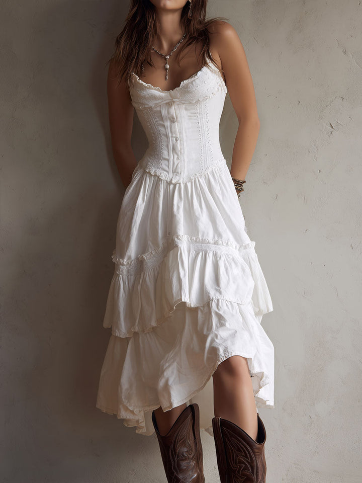 White midi dress with tiered ruffles, fitted bodice, worn with brown boots. Neutral textured background.