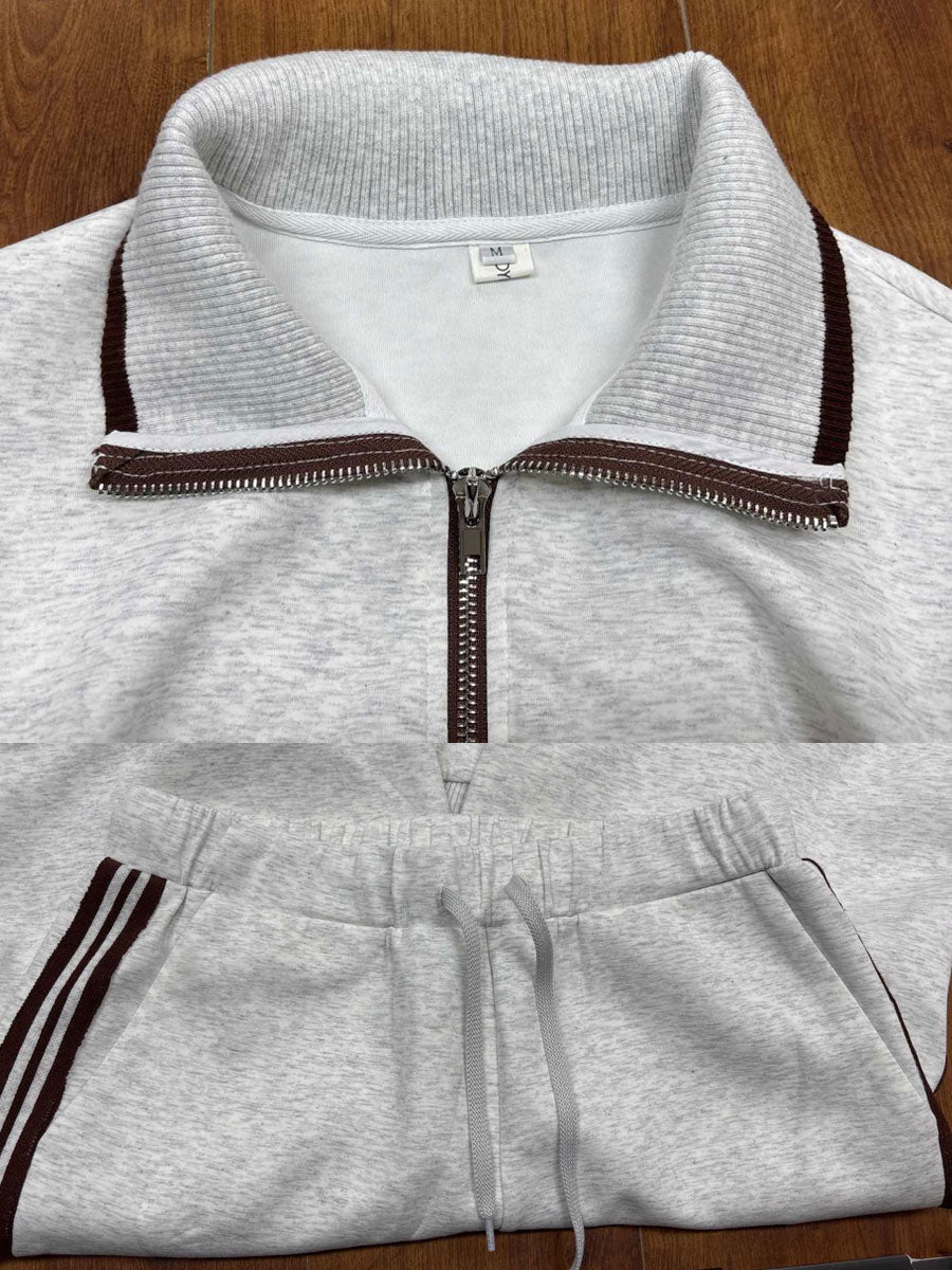 Close-up of light gray half-zip top with striped collar and pants, displayed on a wooden surface.