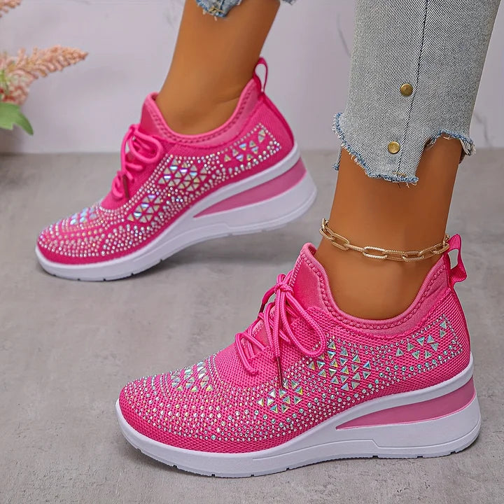 Bright pink orthopedic sneakers with sparkling details, worn with distressed jeans in a soft indoor setting.