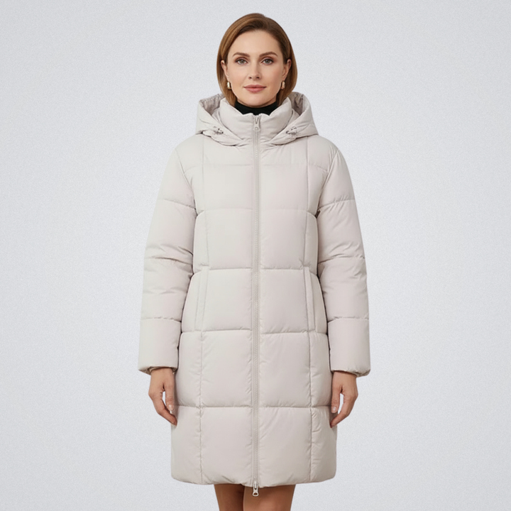 Woman in a cream puffer coat with hood, standing against a plain white backdrop.