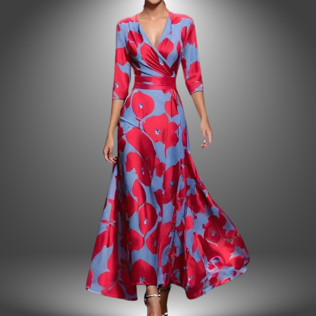 Woman in a long, flowing dress with vibrant red and blue floral pattern, set against a soft gradient studio background.