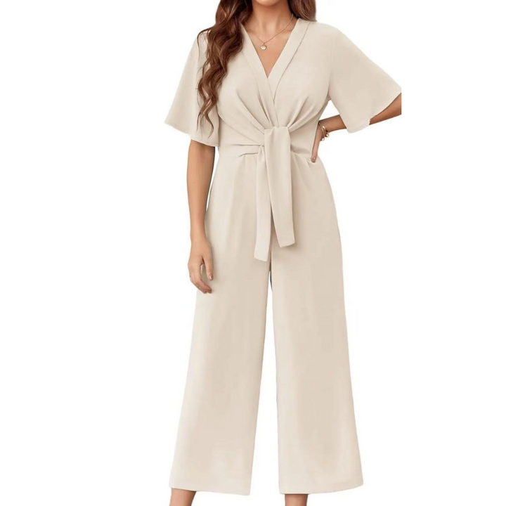 Cream elegant jumpsuit with short sleeves and a tie waist on a woman, studio background.
