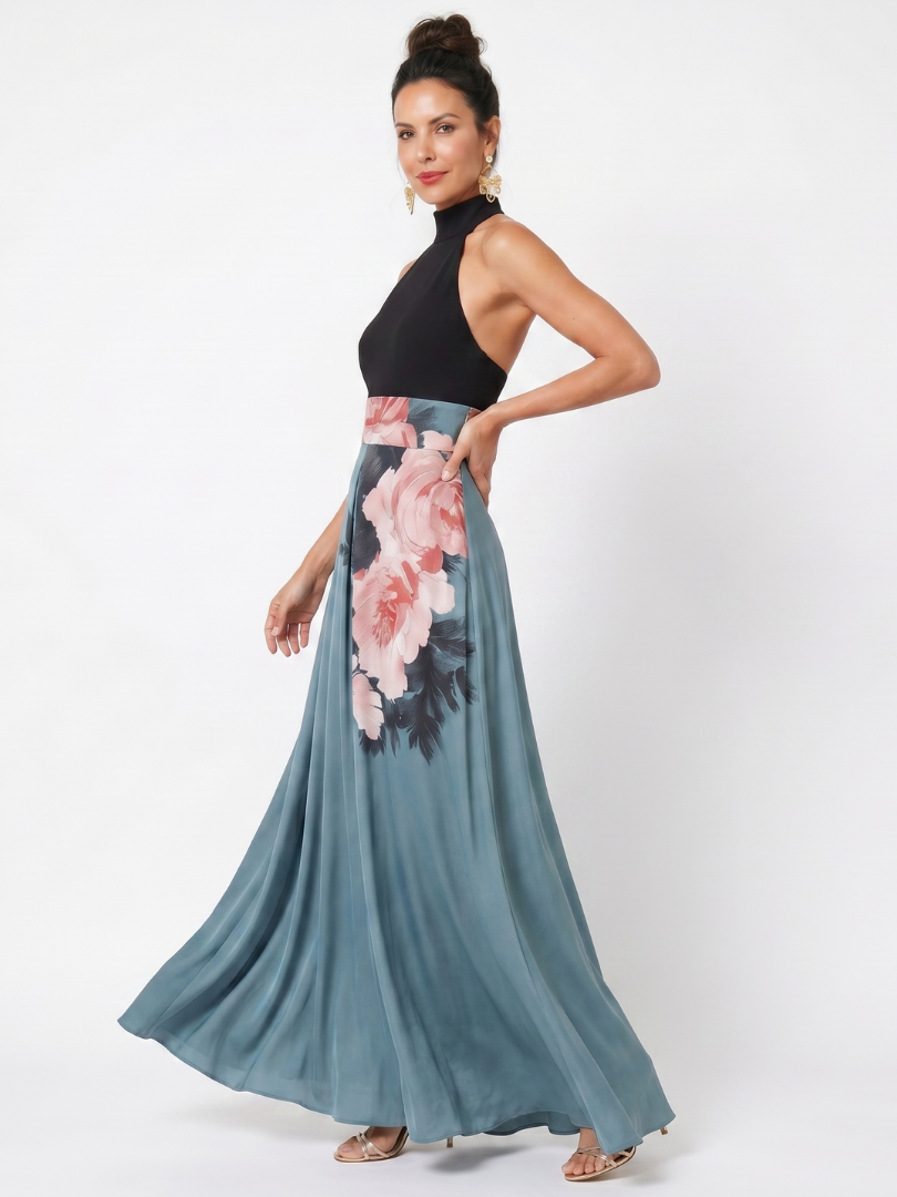 Side view of model in a maxi dress showing black halter top and flowing floral skirt, studio setting.