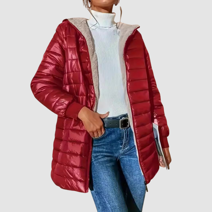 Woman in a red winter coat paired with a white turtleneck and blue jeans, holding a book, studio setting.