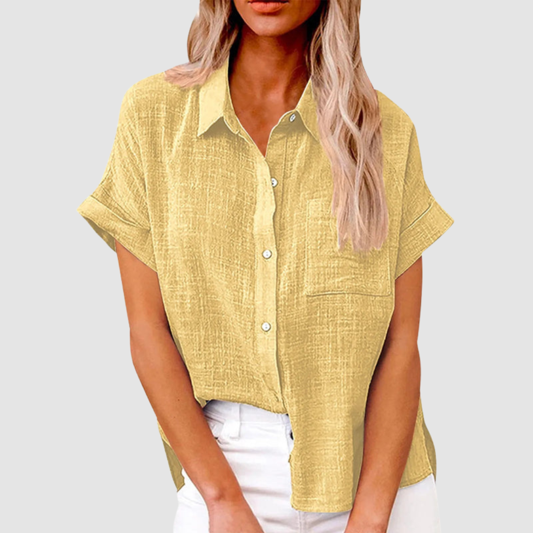 Yellow casual blouse with short sleeves and front buttons, worn in white jeans. Studio background.