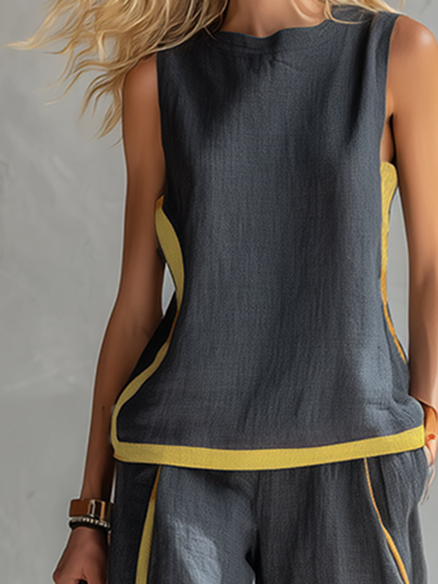 Close-up of dark sleeveless top with yellow sides and trim, worn by a model in a textured gray studio setting.