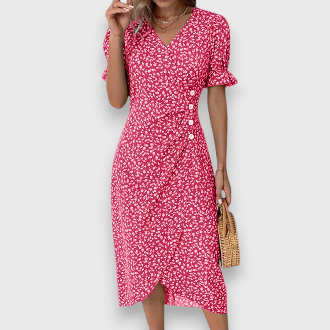 Red floral dress with ruffled sleeves and button detail, woman holding handbag, studio backdrop.