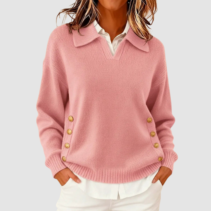 Elegant pink knitted sweater with gold buttons on sides, worn over a white shirt against a light grey background.