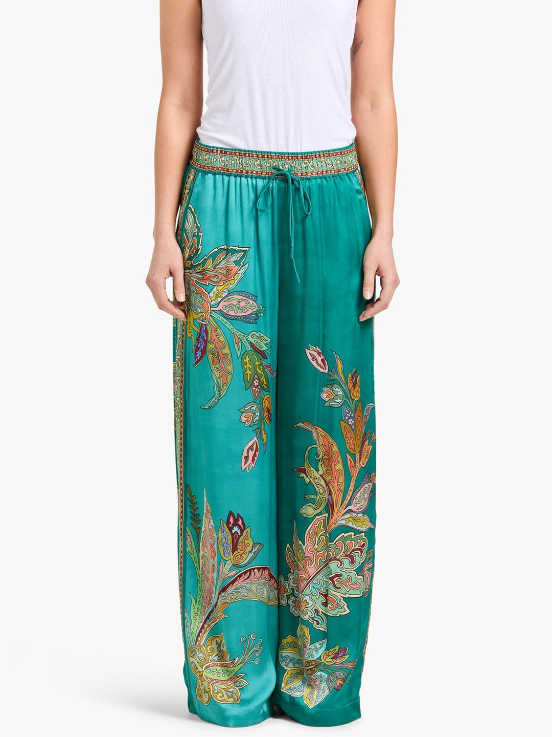 Vibrant green pants with paisley design, elastic waistband, paired with a white tank top, studio setting.