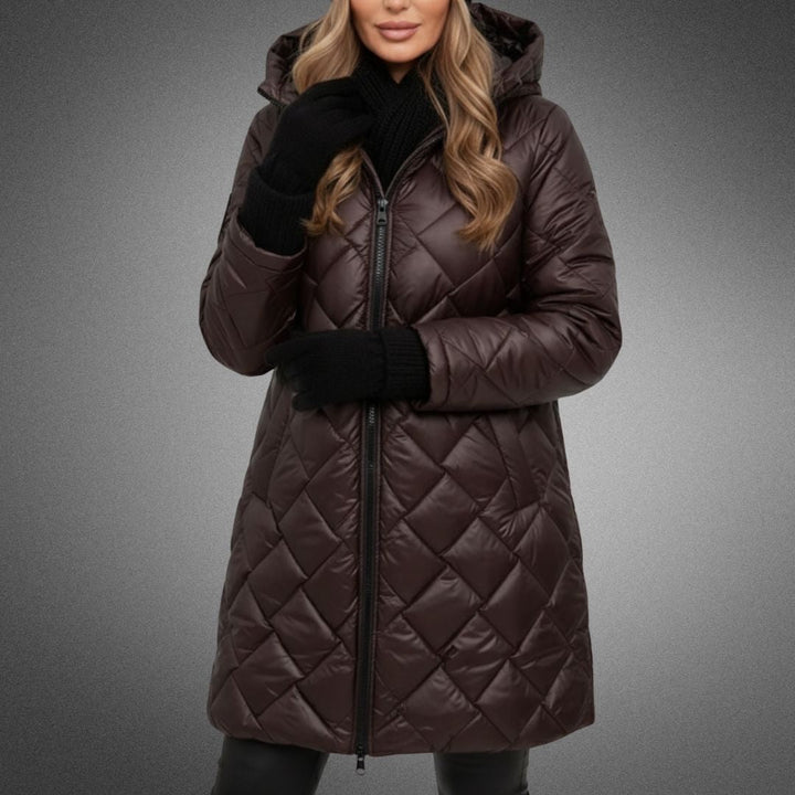 Woman in dark brown quilted jacket with hood in studio, wearing black accessories on a gradient background.