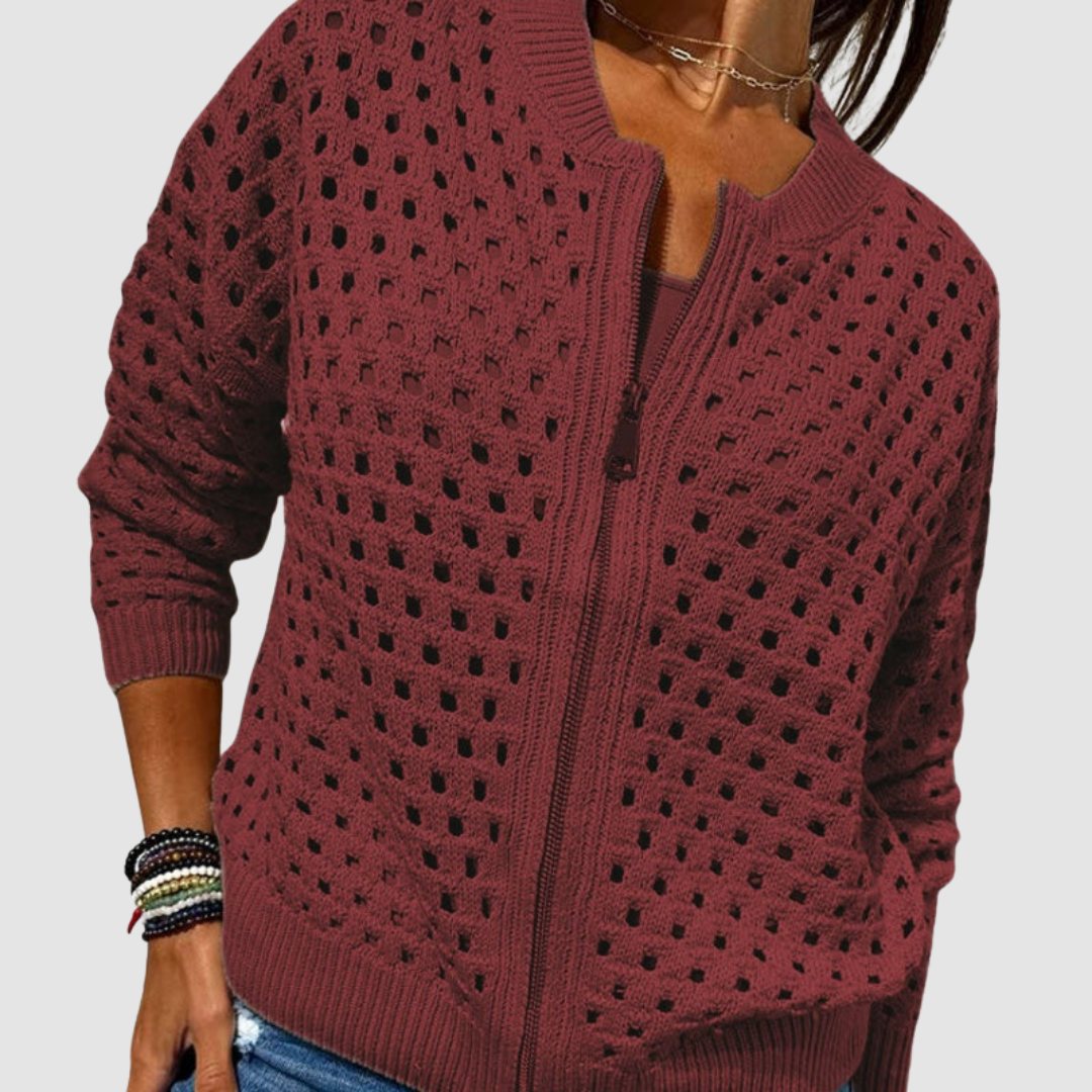Burgundy knitted cardigan featuring a zip front and perforated texture, paired with jeans in a studio environment.