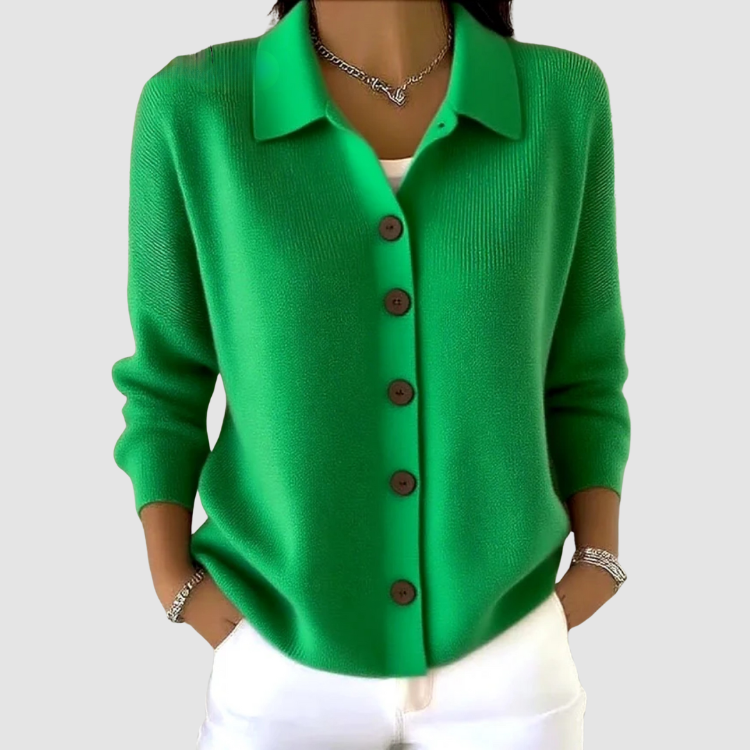 Bright green button-up knit cardigan with brown buttons, worn with white pants in a studio setting.